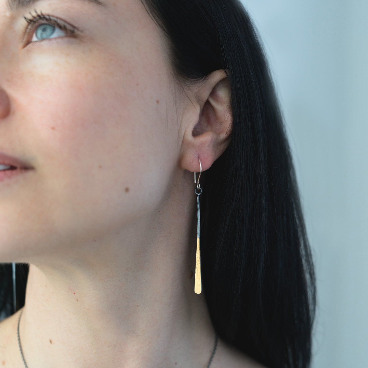 woman wearing oxidized silver and gold bar earrings
