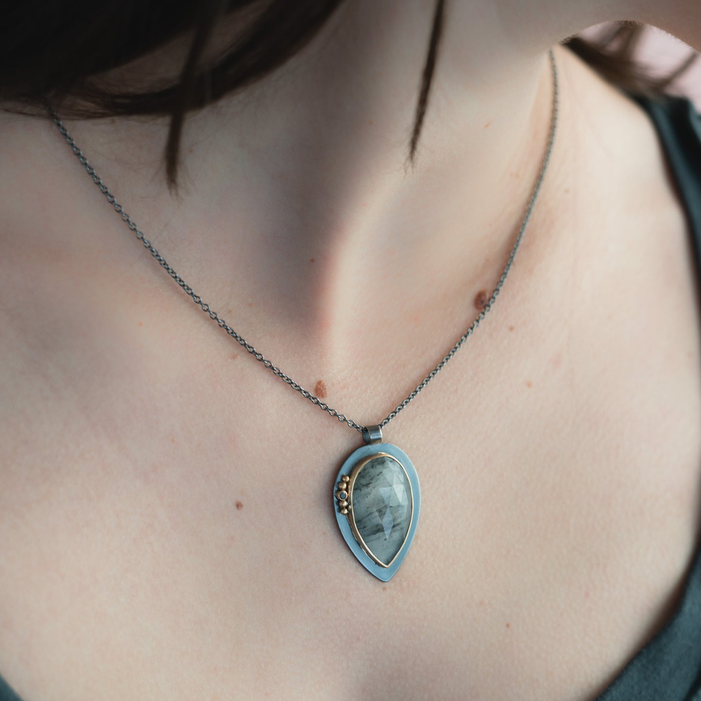 woman wearing oxidized silver pendant with grey rose cut stone and black diamond