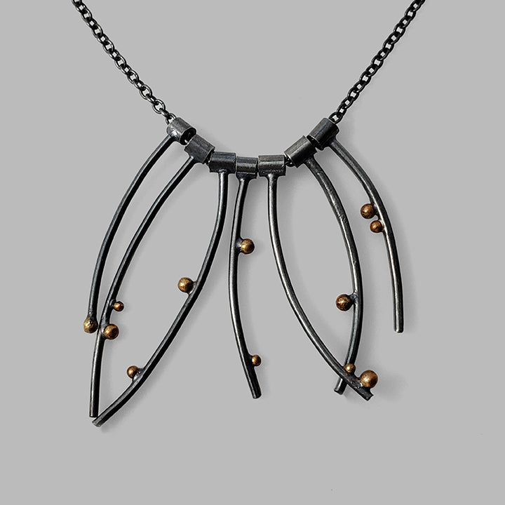 multiple curved oxidized silver wires with gold dots on chain