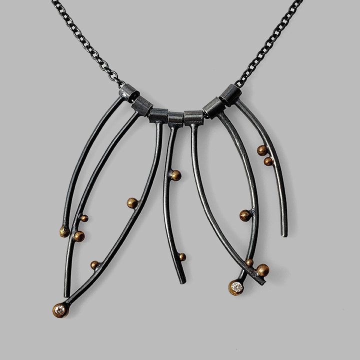multiple curved oxidized silver wires with gold dots and gemstones on chain