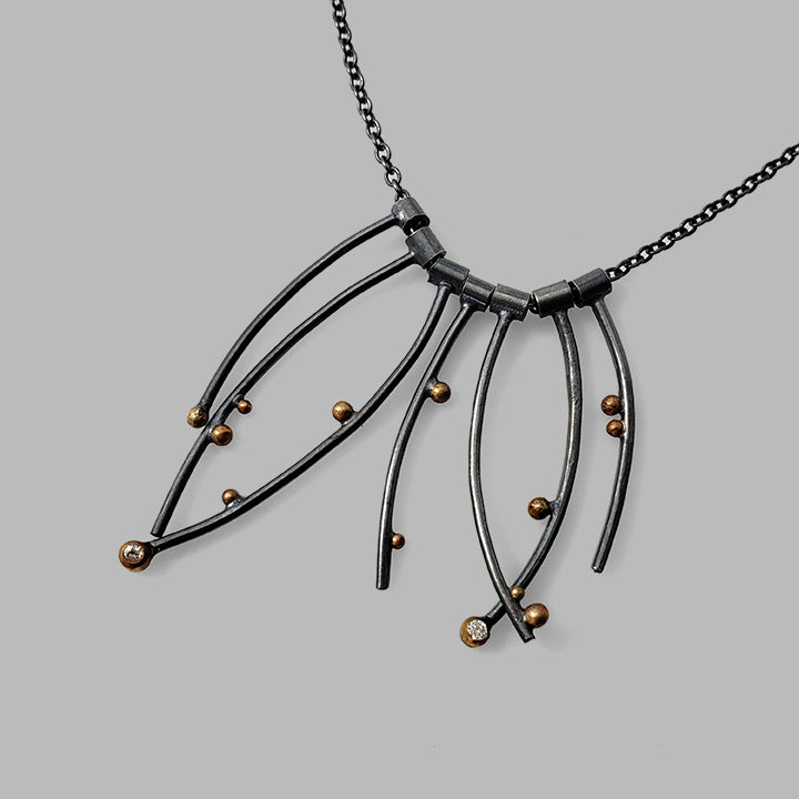 multiple curved oxidized silver wires with gold dots and gemstones