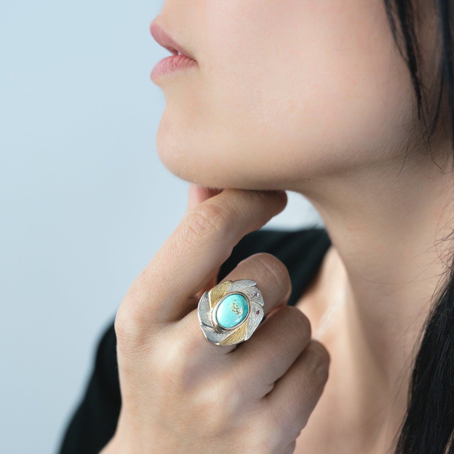woman wearing teal and pink mixed metal gemstone ring