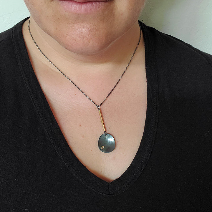 handmade oxidized organic silver pendant with diamond hangs from gold bar