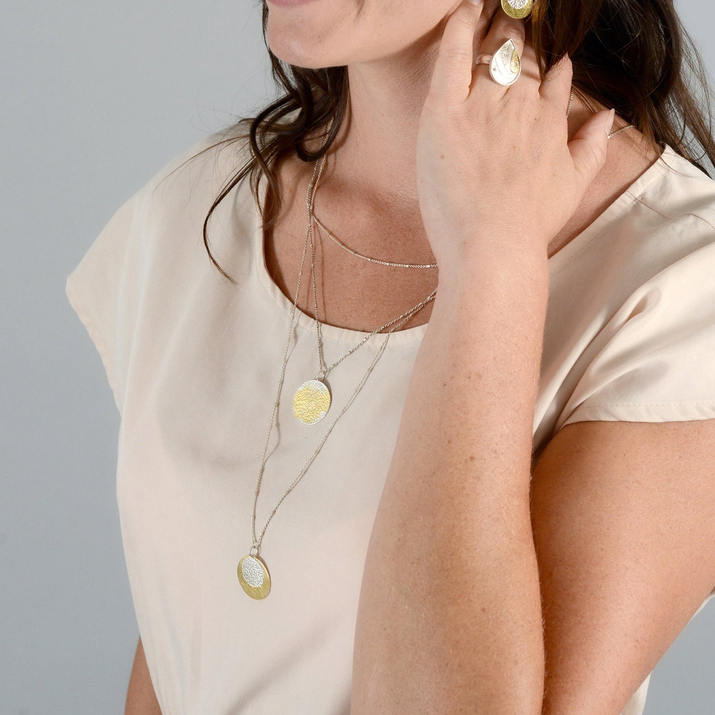 woman wearing layered silver necklaces