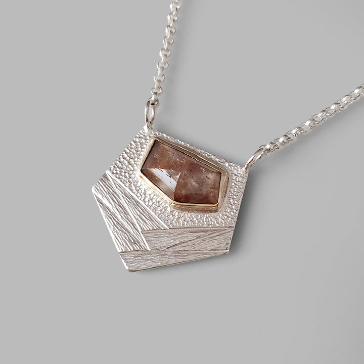textured silver pendant with orange rose cut gemstone set in yellow gold