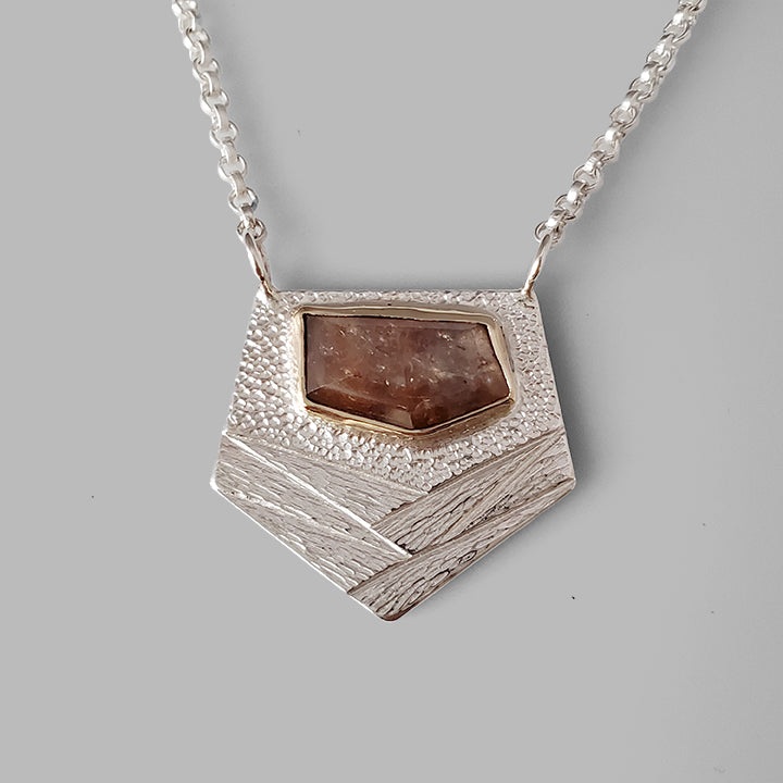 Silver textured pendant with orange faceted gemstone set in gold