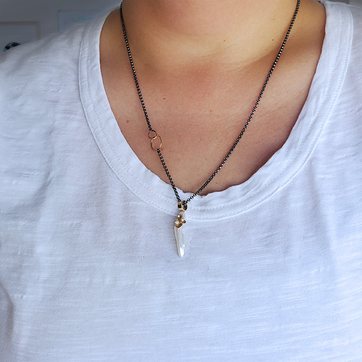 organic stick shaped pearl with gold cup accents on an oxidized silver chain with gold hoops