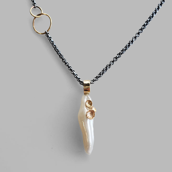 white organic stick shaped pearl with gold cup accents pendant on an oxidized silver chain
