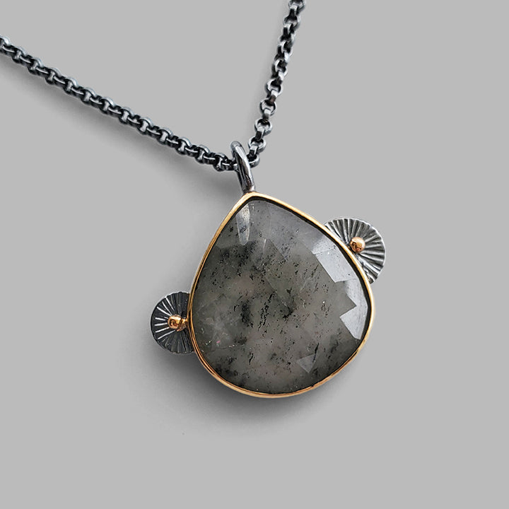 black and white faceted teardrop gemstone set in gold bezel with dark silver accents on oxidized chain