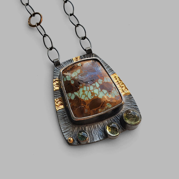 oxidized textured silver and gold pendant with green and brown gemstones on oval link chain