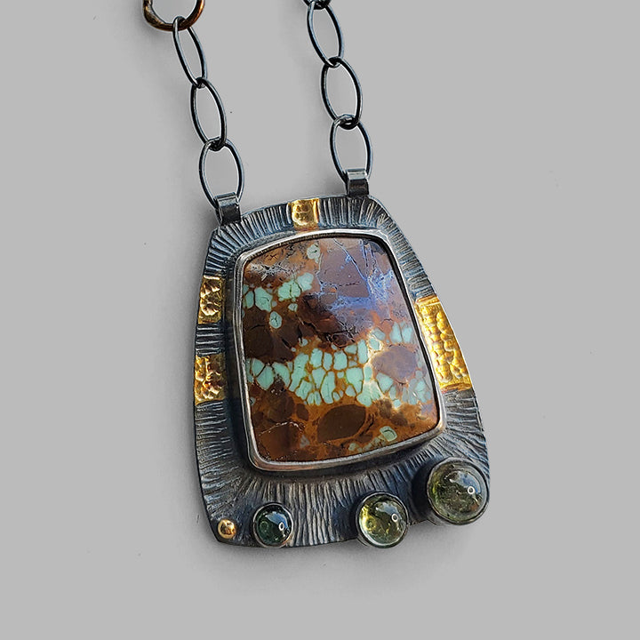 oxidized textured silver and gold pendant with green and brown gemstones