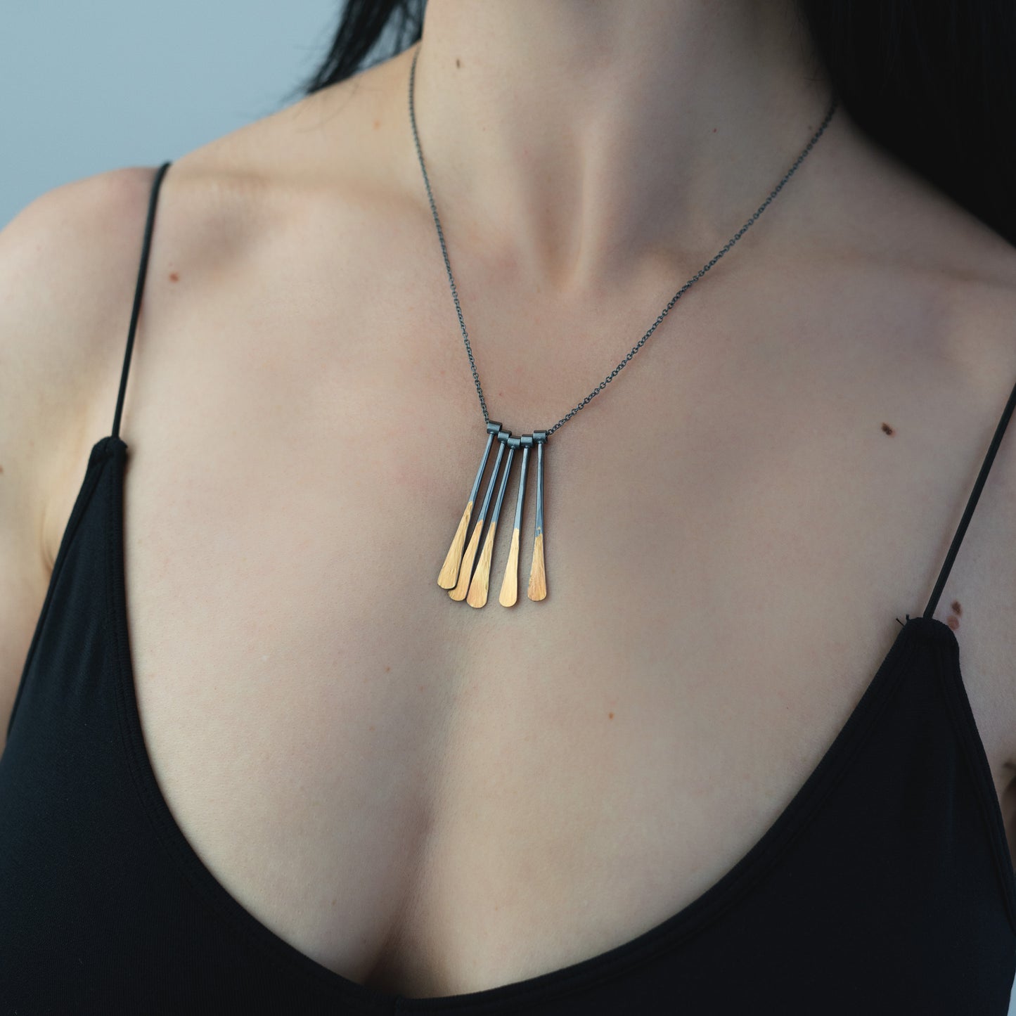 woman wearing hammered oxidized silver and gold bar necklace