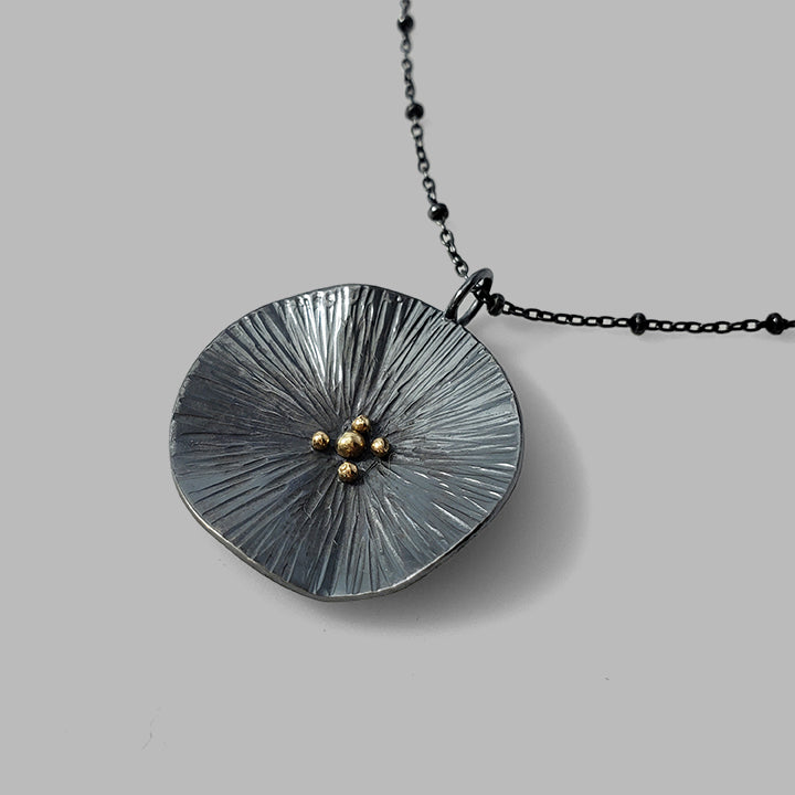 round textured organic oxidized silver pendant with gold dots on chain