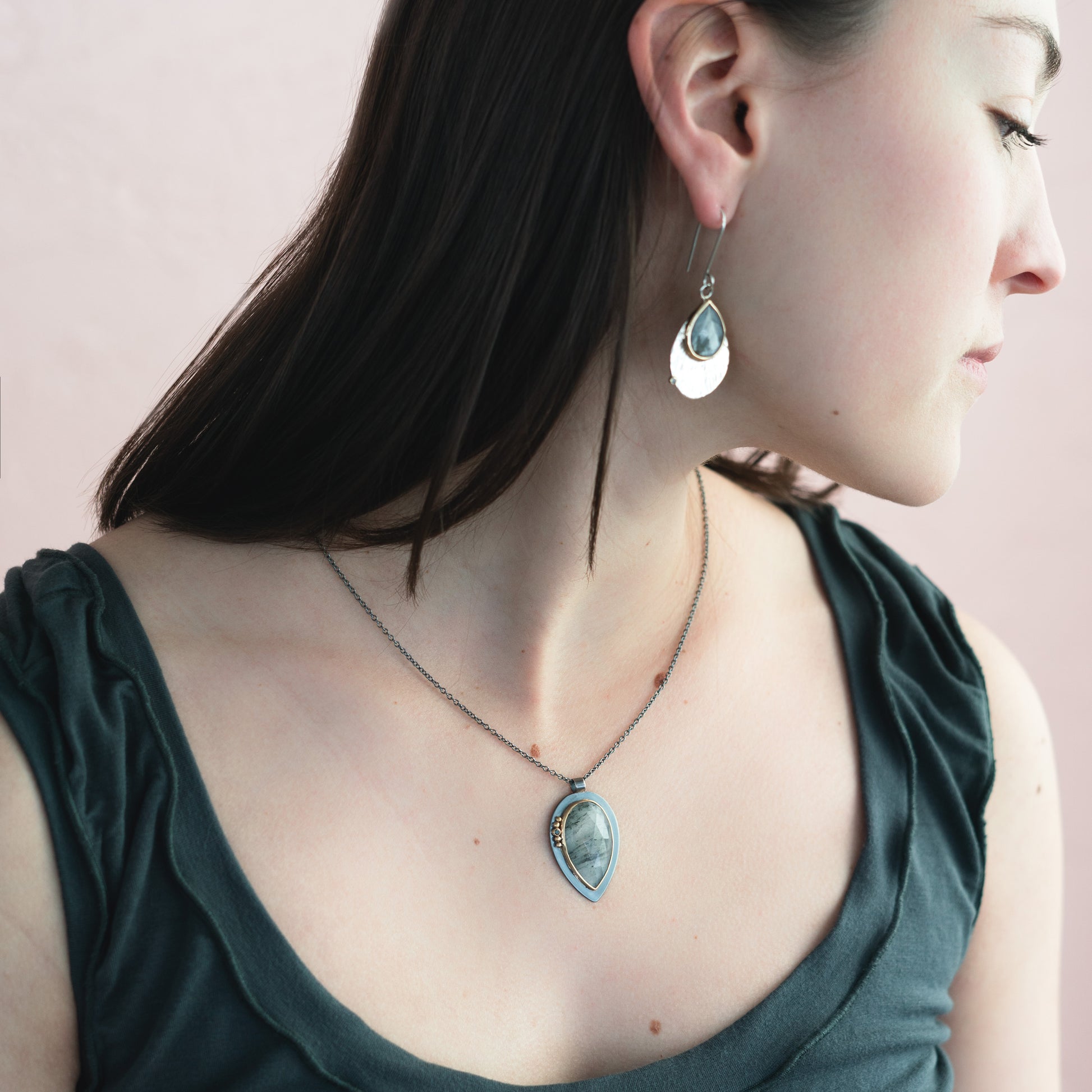 lady wearing dark metal pendant with rose cut center stone on long chain