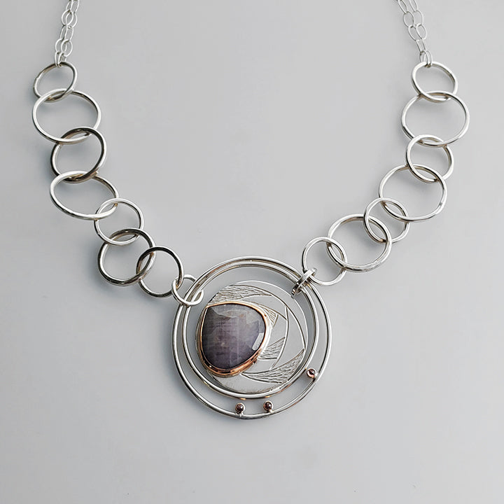 large silver textured pendant with teardrop shaped pink gemstone set in rose gold