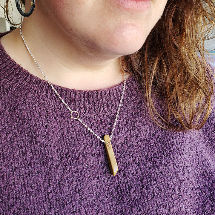 brown stick shaped stone on silver chain with diamond