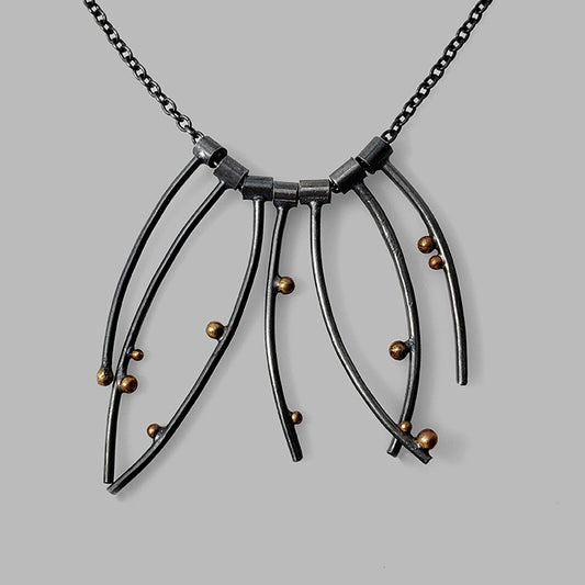 multiple curved oxidized silver wires with gold dots on chain