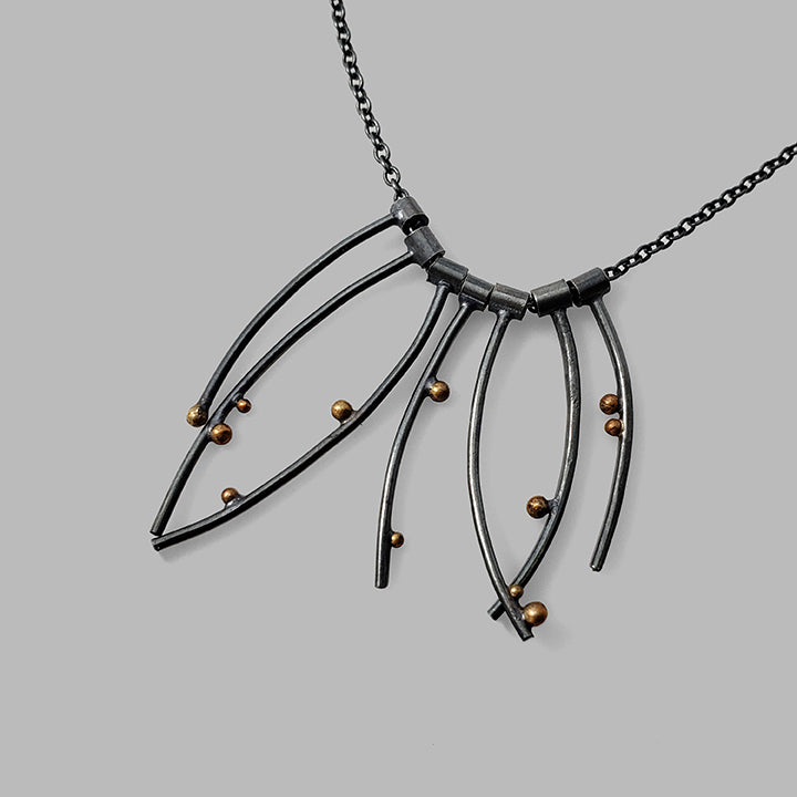 multiple curved oxidized silver wires with gold dots on chain