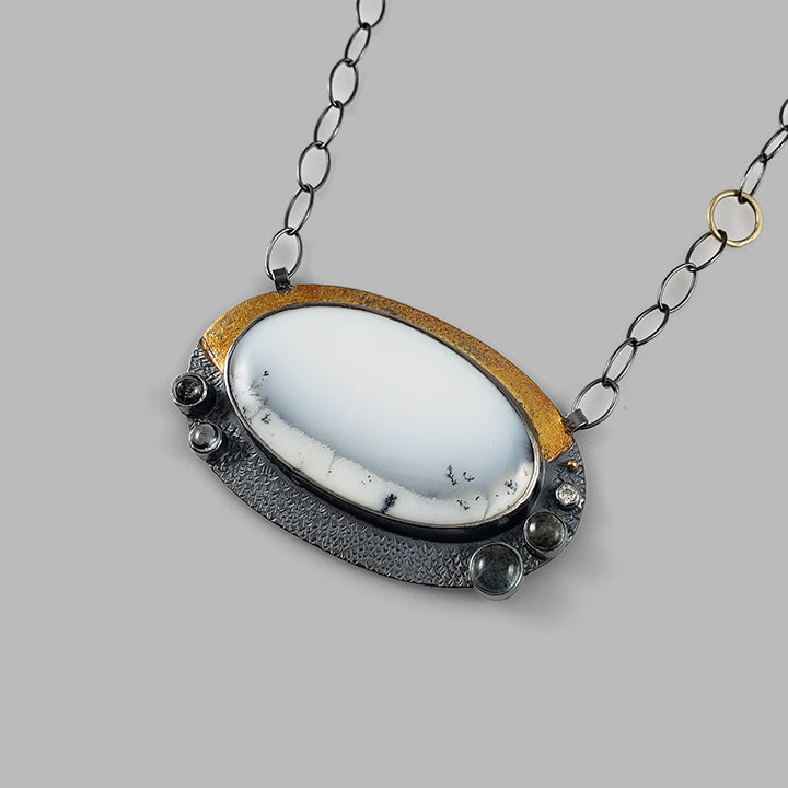 unique mixed metal oxidized silver and gold pendant with white and black stone with blue stone accents